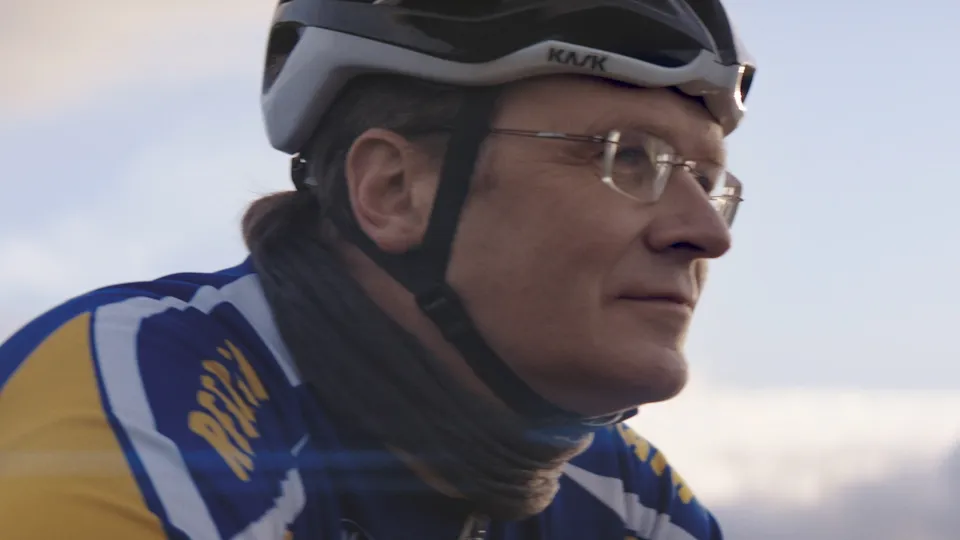 Radfahrerin mit Kask-Helm und Brille in blau-gelber Sportkleidung im Profil