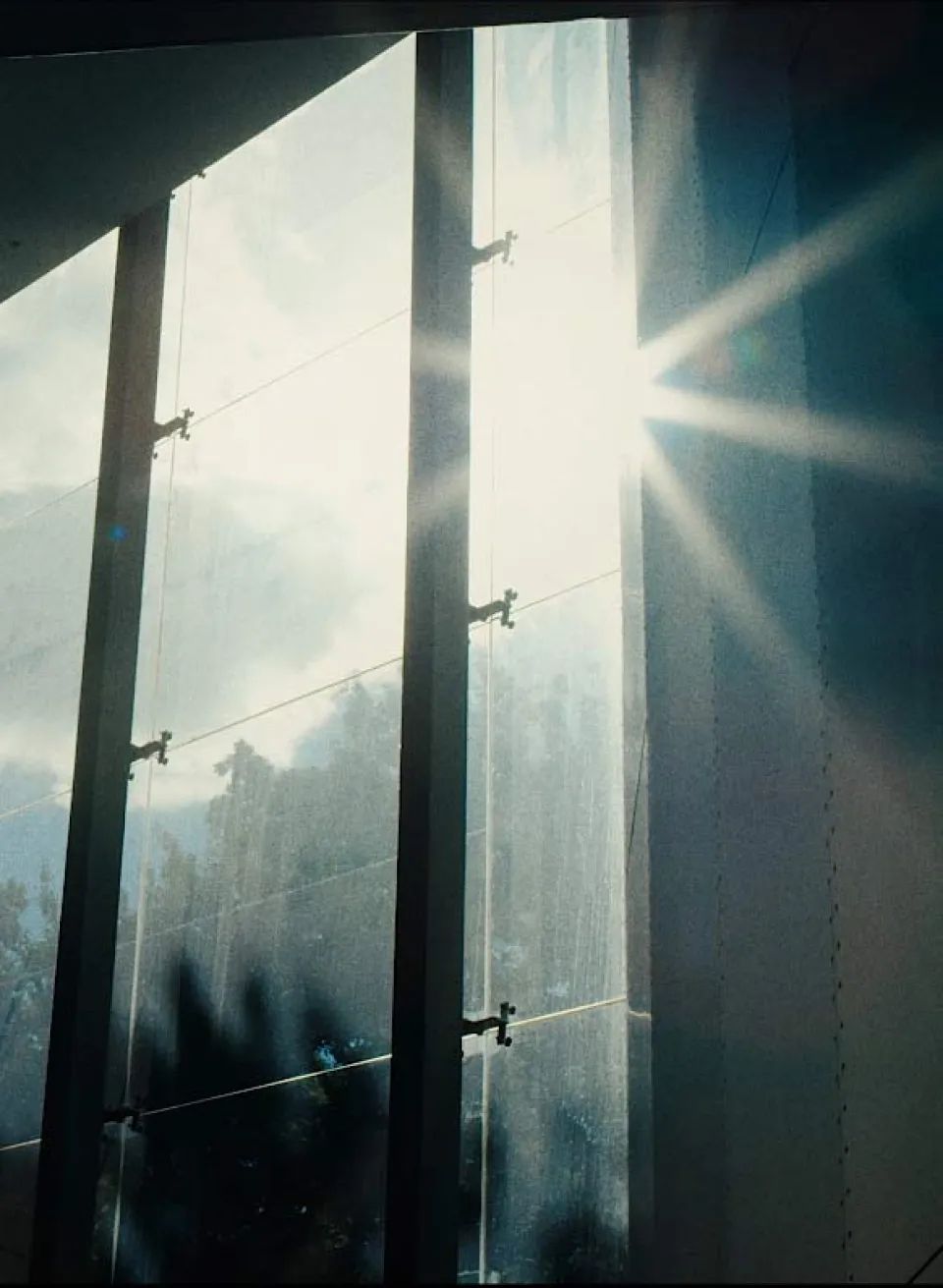 Sonnenlicht fällt durch hohe Betonwände und erzeugt dramatische Licht- und Schattenspiele mit sichtbaren Lichtstrahlen in staubiger Luft.