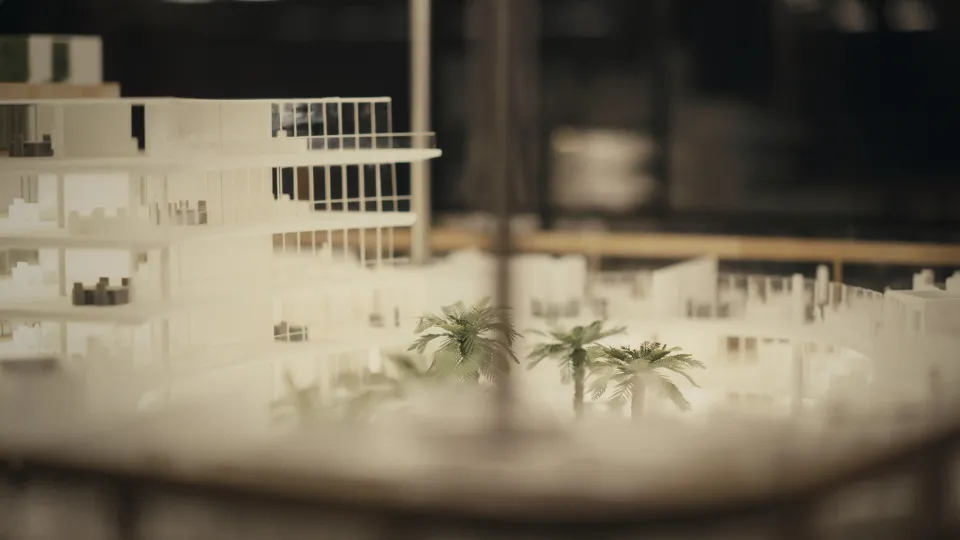 Architekturmodell eines modernen mehrstöckigen Gebäudes mit Miniatur-Palmen im Vordergrund