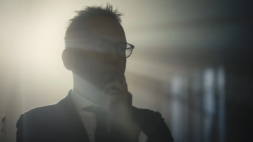 Silhouette einer Person mit Brille und kurzem Haar im Gegenlicht, Profil von der Seite aufgenommen.