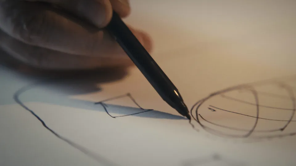 Hand zeichnet mit schwarzem Stift eine Skizze auf Papier