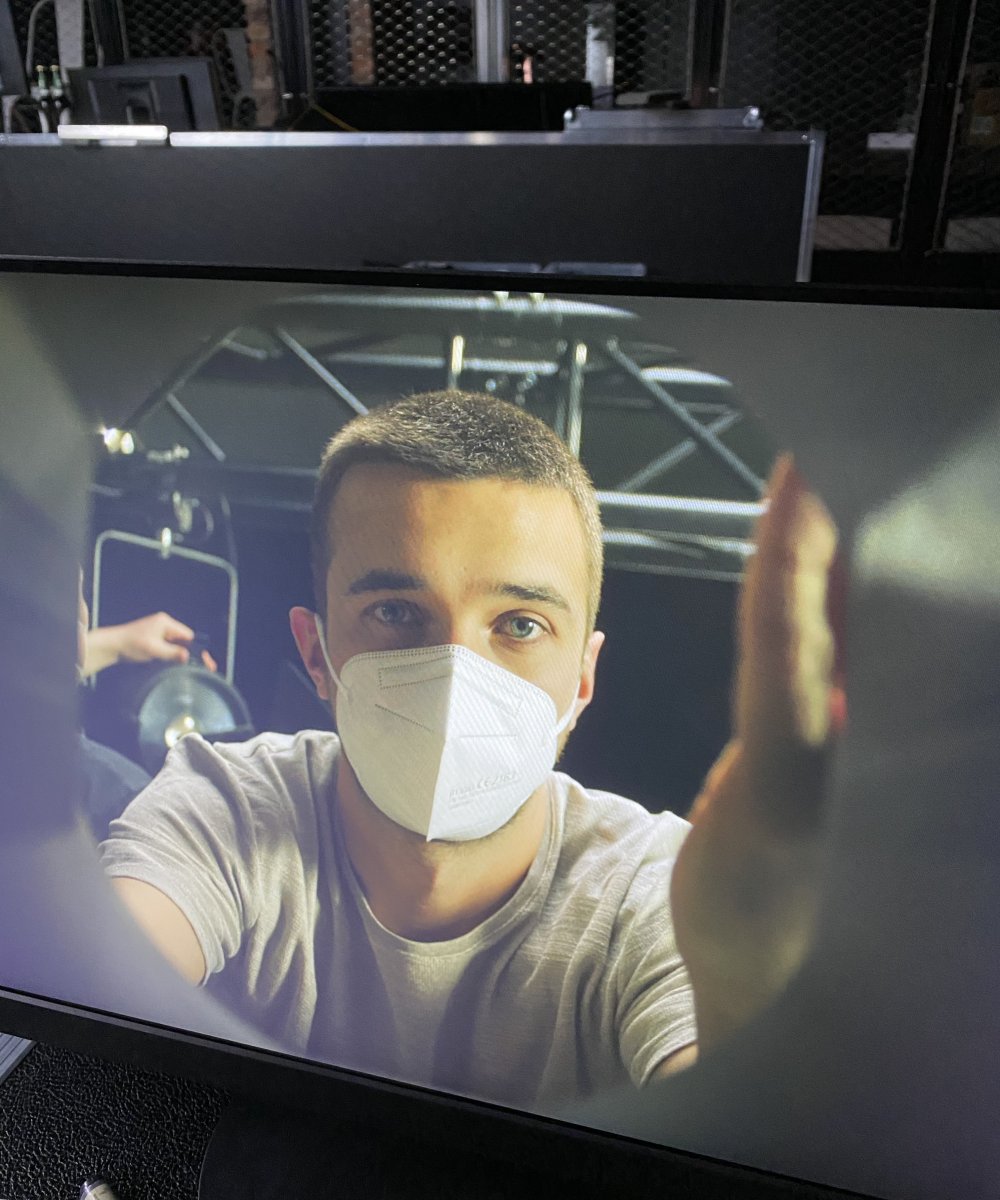 Person mit weißer FFP2-Maske macht ein Selfie in einem Tonstudio mit schallgedämmten Wänden
