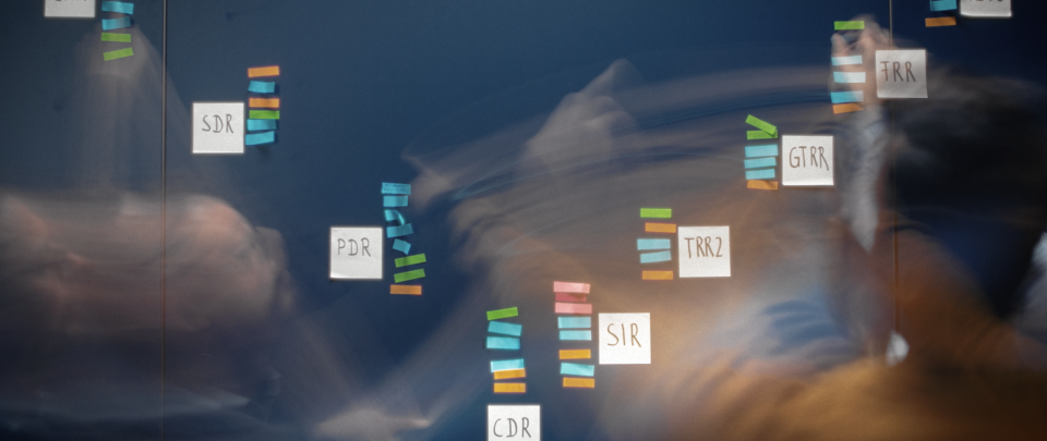 Wissenschaftliche Darstellung von DNA-Reparaturwegen mit farbcodierten Sequenzen und Beschriftungen wie SDR, PDR, GTRR, TRR2, SIR und CDR über einem unscharfen Hintergrund mit Händen.