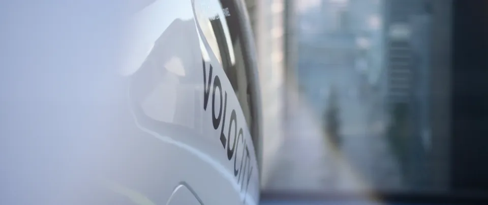 Nahaufnahme einer Volvo-Heckklappe mit Logo und Schriftzug vor verschwommenem städtischem Hintergrund