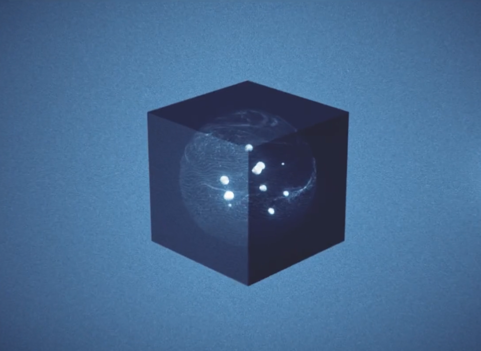 Dunkelblauer Würfel mit eingelaserten Planeten und leuchtenden weißen Punkten, die ein Sonnensystem darstellen, vor blauem Hintergrund.