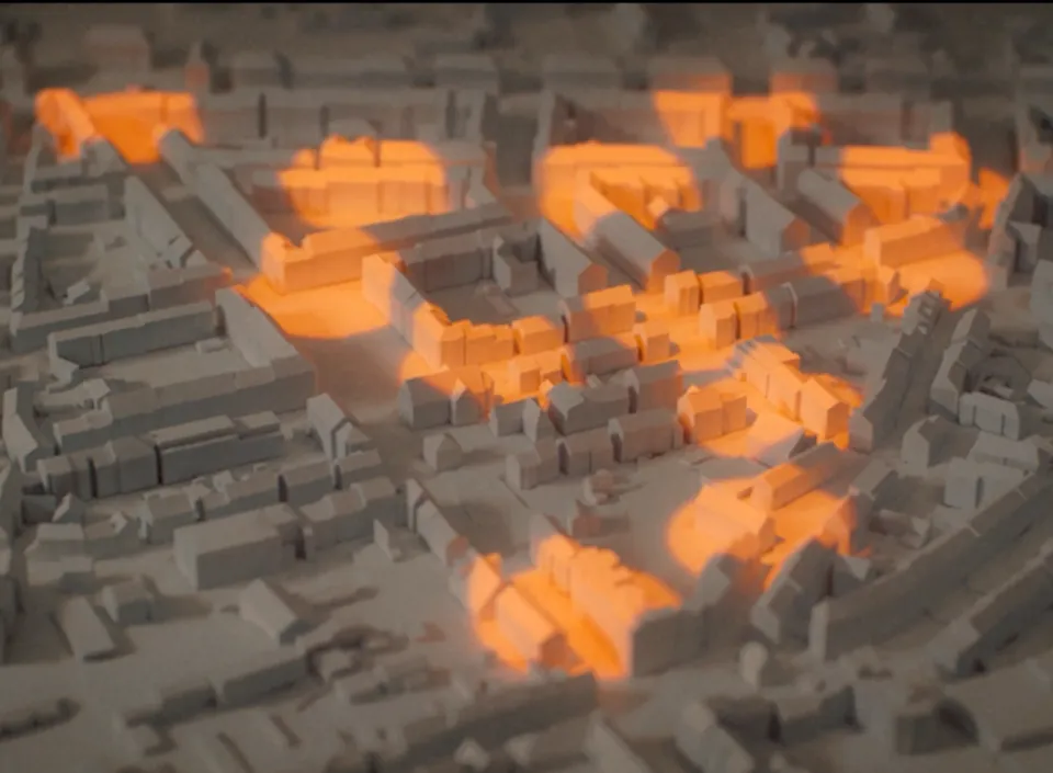 3D-Stadtmodell mit grau dargestellten Gebäuden und orange hervorgehobenen Bereichen zur Visualisierung von Daten oder Analysen.