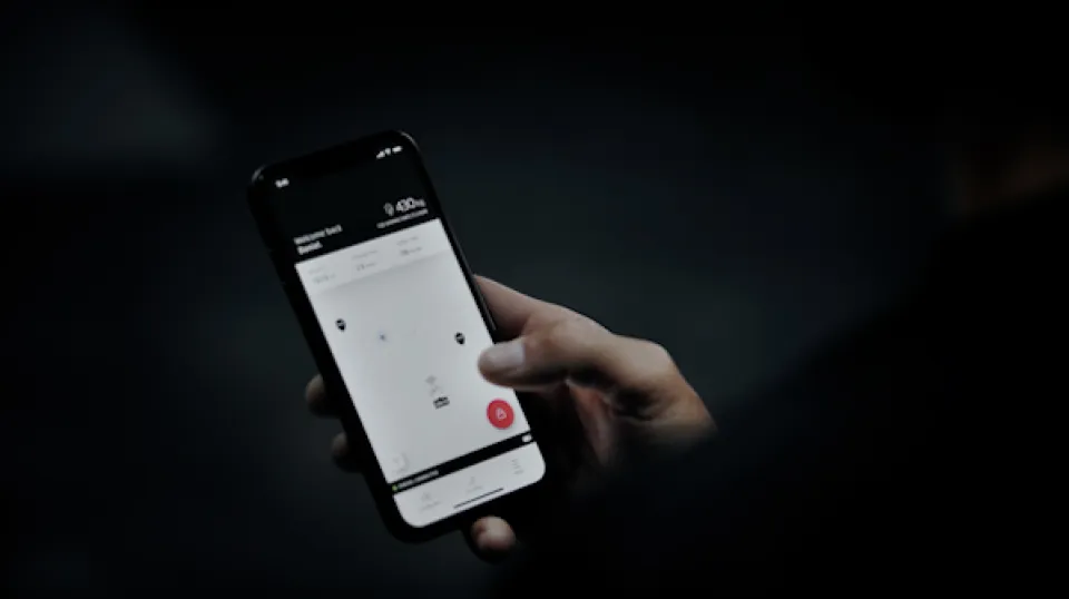 Hand hält Smartphone mit Krypto-Wallet-Interface, das einen Bitcoin-Kontostand von 9,60 $ anzeigt, mit rotem Aktionsbutton in der Mitte.